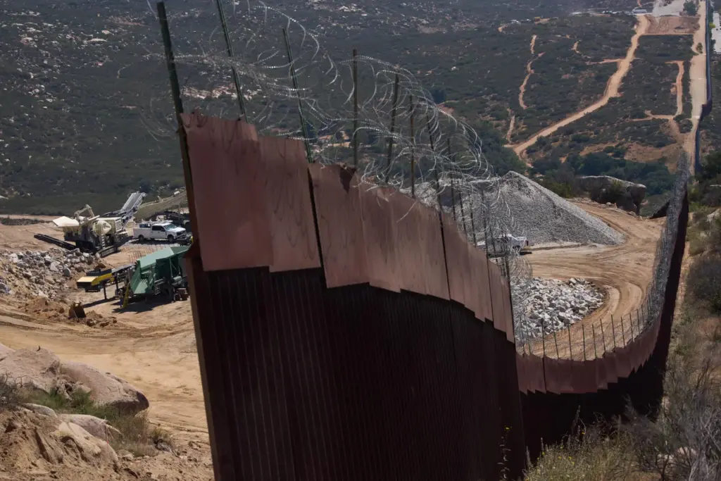 Construction crews work on a new border wall segment near...