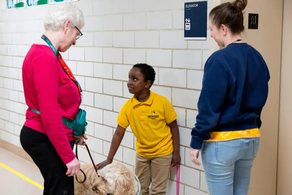 Second grader Samuel stops in the hallway to pet Sage,...