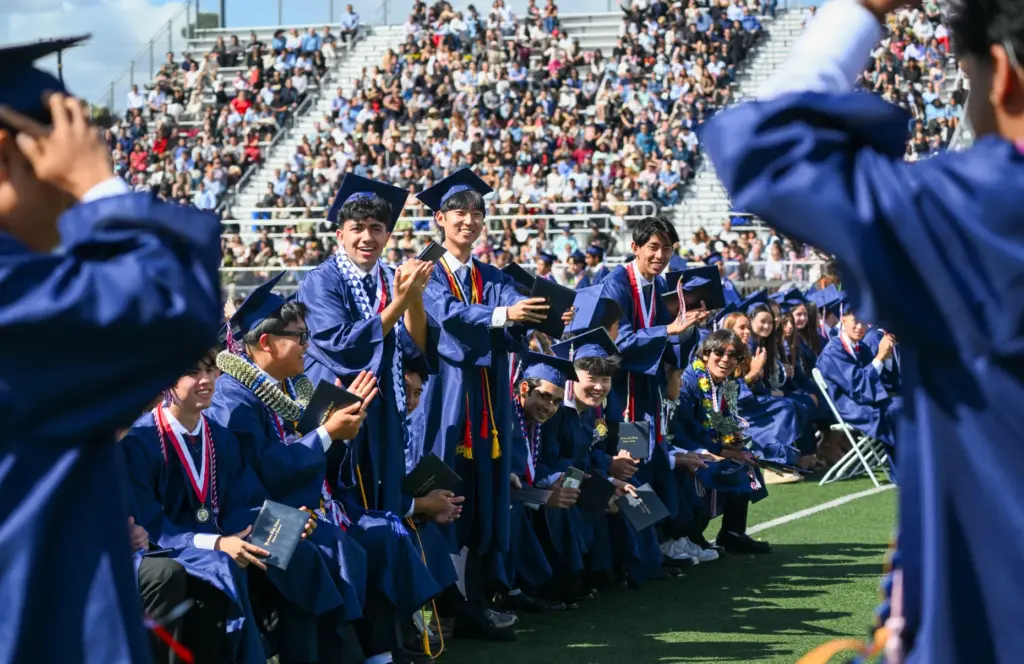 Graduates cheer as names are called for other graduates during...