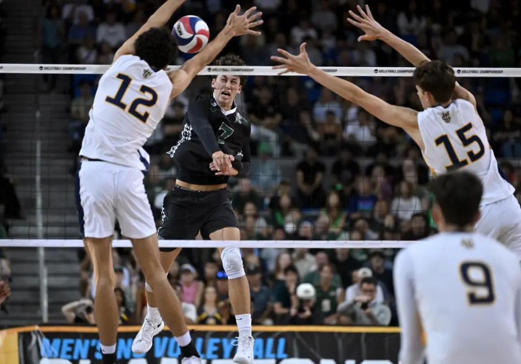 Hawaiiâs Adrien Roure, middle, spikes the ball during the NCAA...