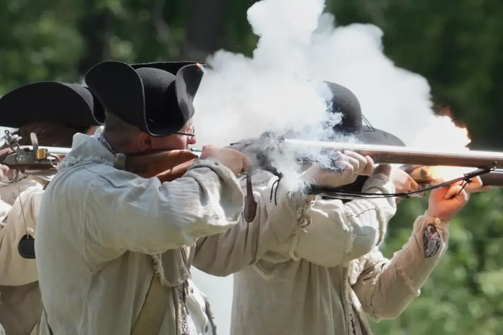 Re-enactors fire a volley with their flintlock muskets during a...