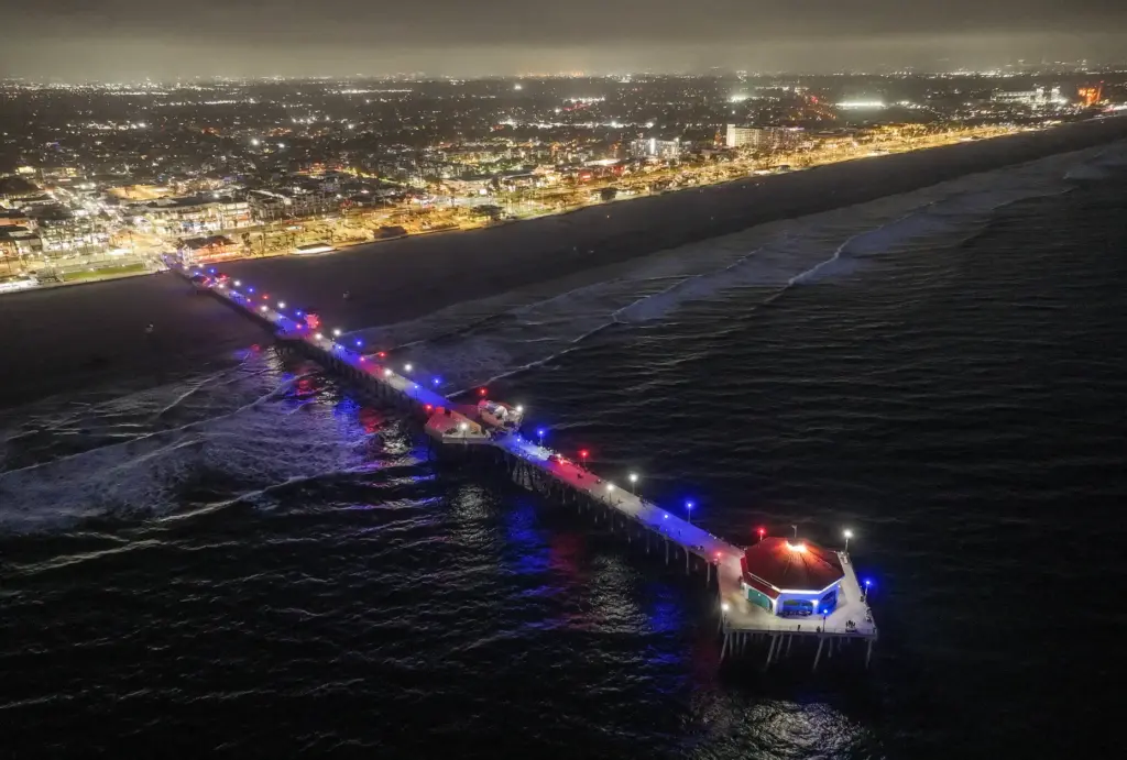 The Huntington Beach Pier is lit in red, white and...