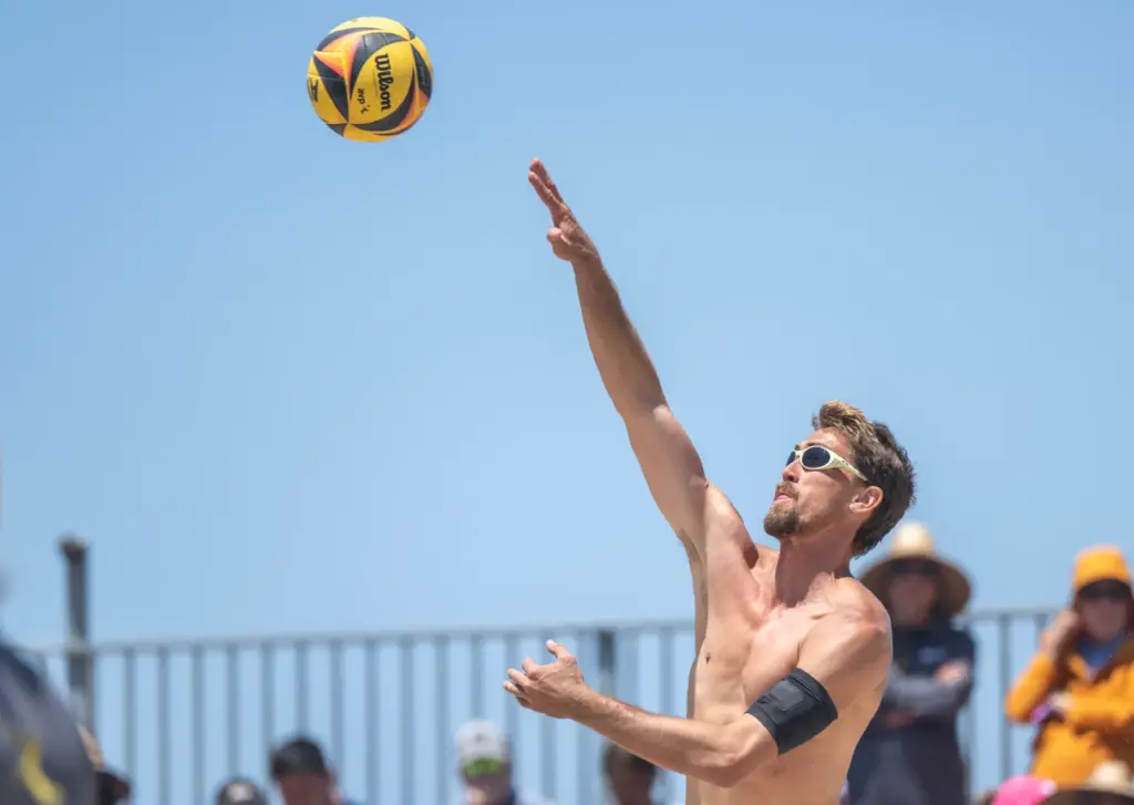 Taylor Crabb serves the ball, while playing with teammate Andy...