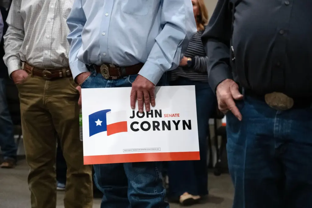 Supporters hold a Sen. John Cornyn, R-Texas, sign.