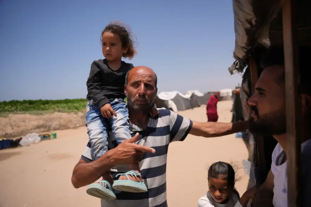Ne'man Abu Jarad carries his granddaughter Hour Abu Jarad as he talks with a neighbor