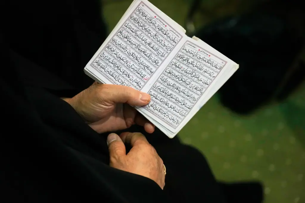 A woman reads passages from Islam’s holy book, the Quran,...
