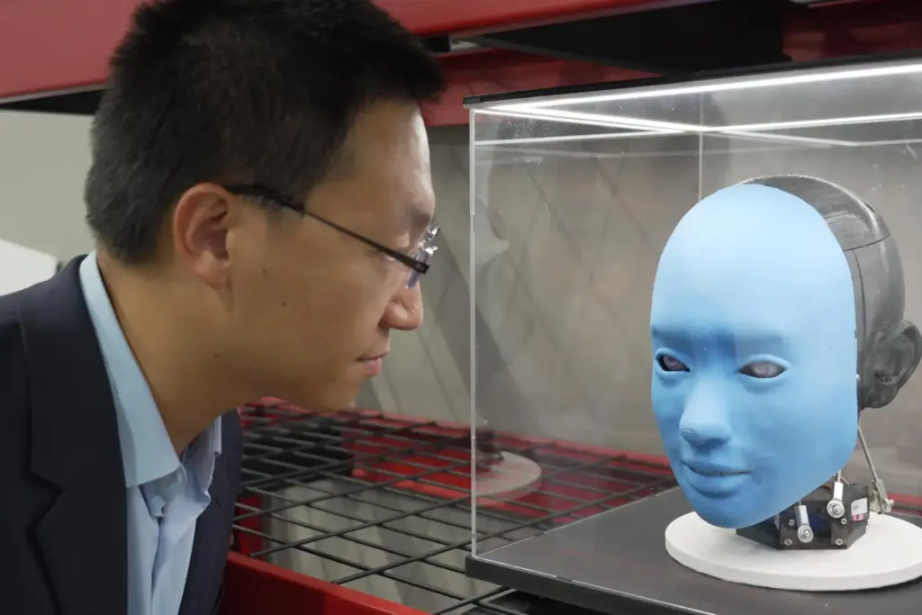 Professor Boyuan Chen is reflected in a glass case as...
