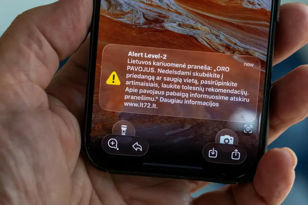 The phone shows the received message “The Lithuanian military reports:...