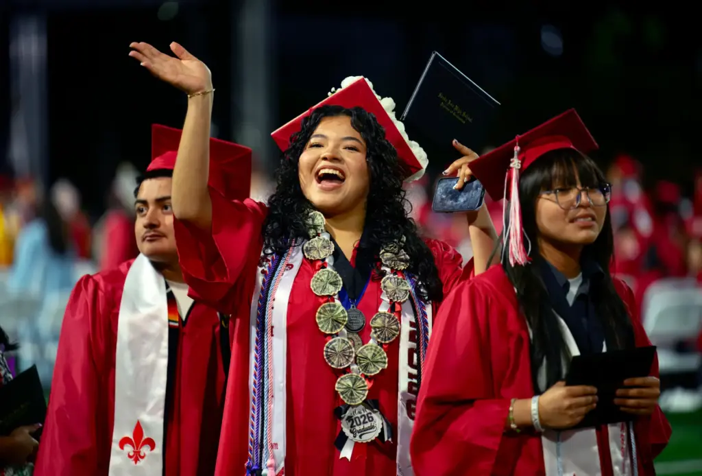 Kimberly Barajas waves to her family after receiving her diploma...