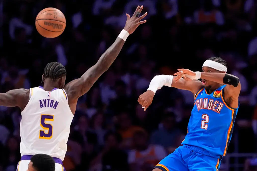 Oklahoma City Thunder guard Shai Gilgeous-Alexander, right, passes the ball...