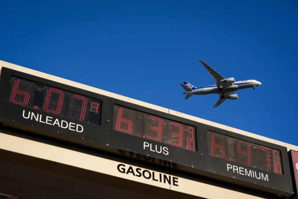 a jet flies above a gas station