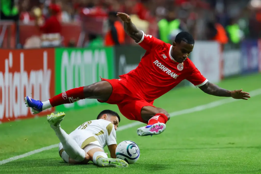 Toluca FC’s Helio Nunes, top, battles for the ball with...