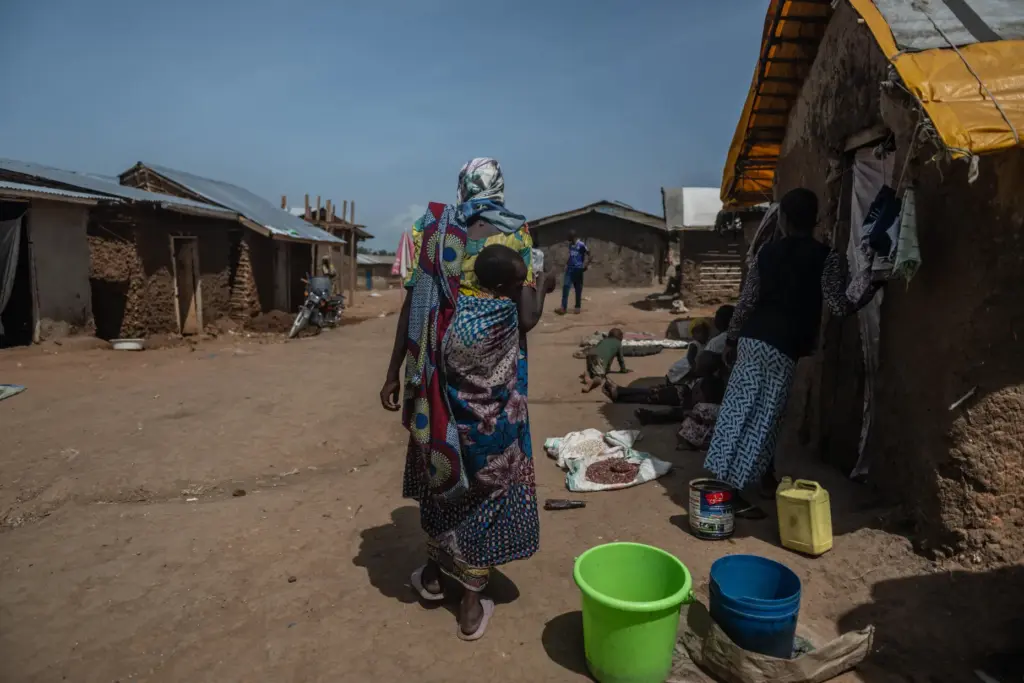 A woman carrying a child walks through the camp.