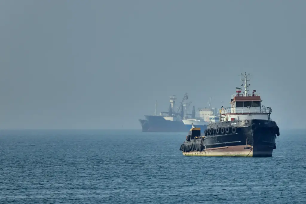 An Iranian tugboat floats as cargo ships sit at anchor in the Strait of Hormuz.