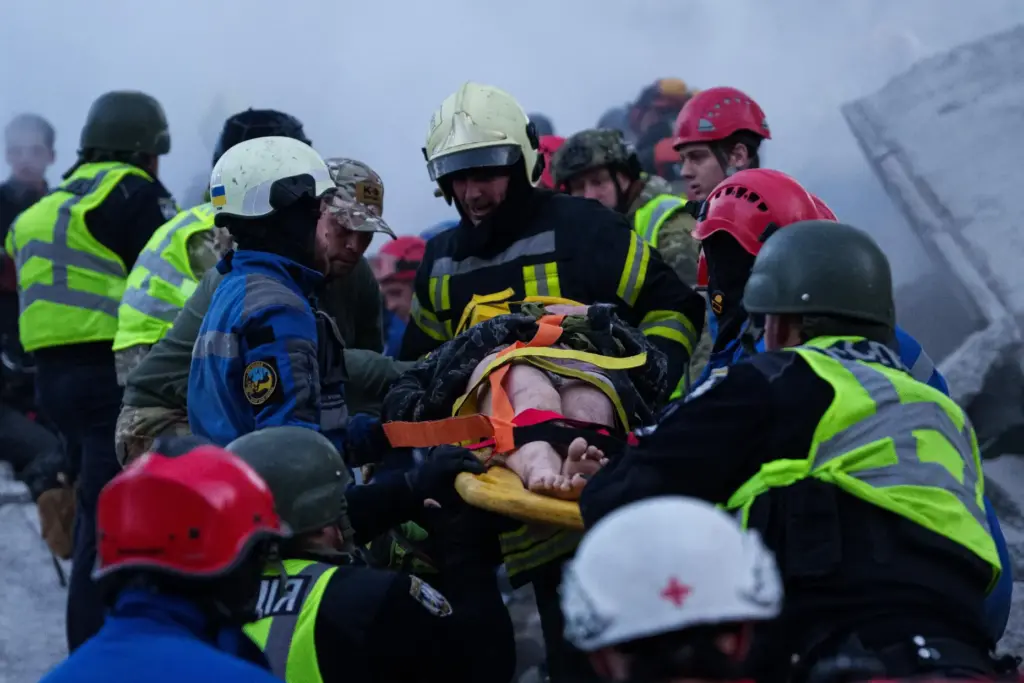 Rescuers carry an injured woman on a stretcher from a house damaged after a Russian strike.