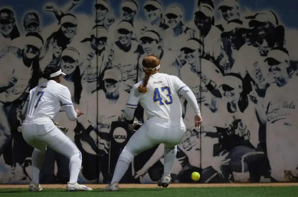 UCLA outfielders Jolyna Lamar, left, and Megan Grant scramble for...