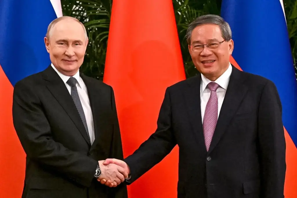 Russian President Vladimir Putin and Chinese Premier Li Qiang shake hands.