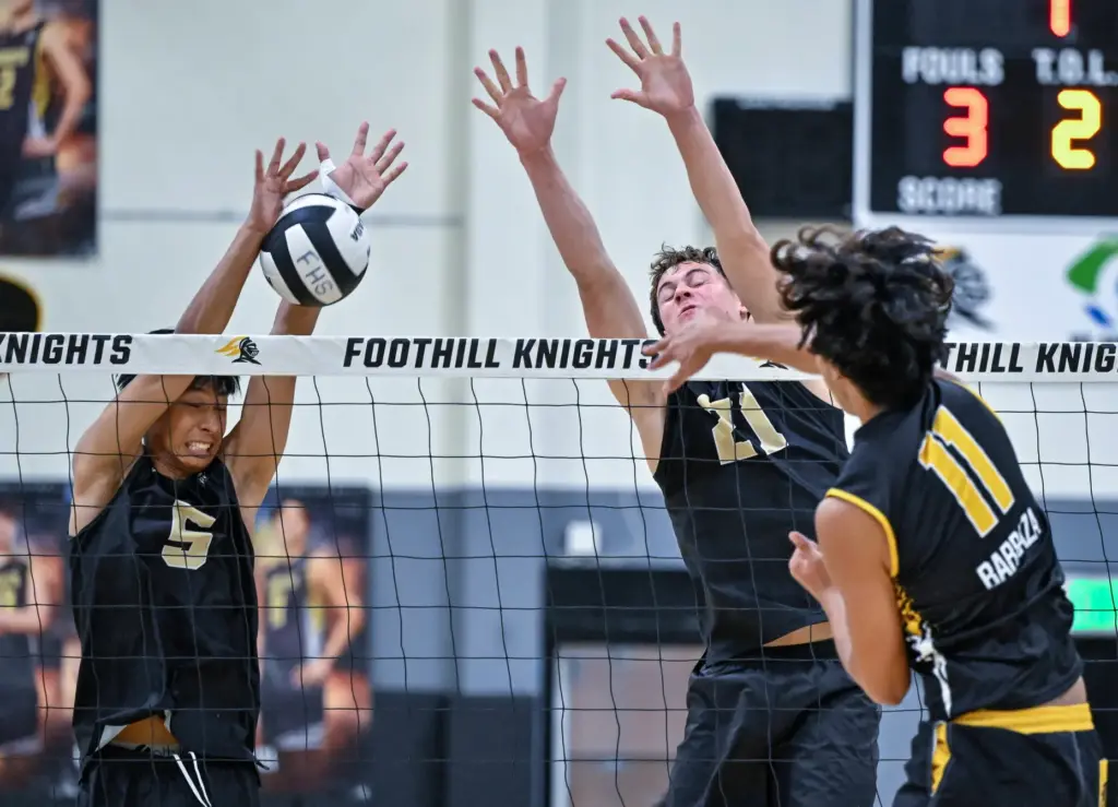 Servite middle blocker Tim Caragaoduring, left, joined by teammate Jake...