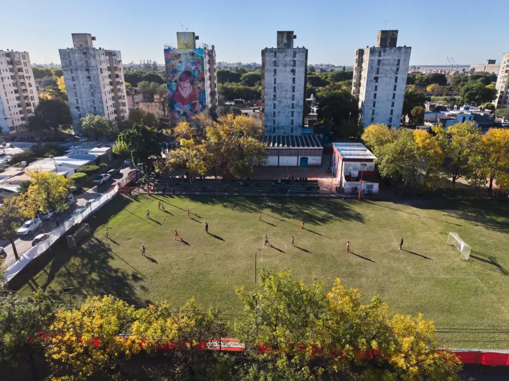 A mural of soccer star Lionel Messi covers the wall of a building as children play soccer