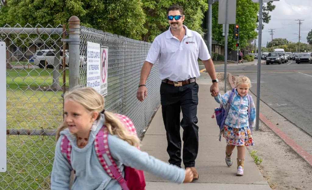 Jonathan Wighton walks his daughters, Alice, 7, left, and Kelly,...