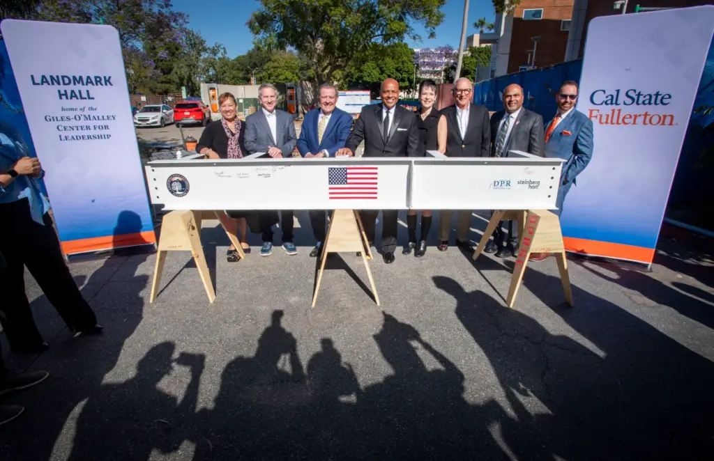 Dignitaries have their photo made near a beam that is...