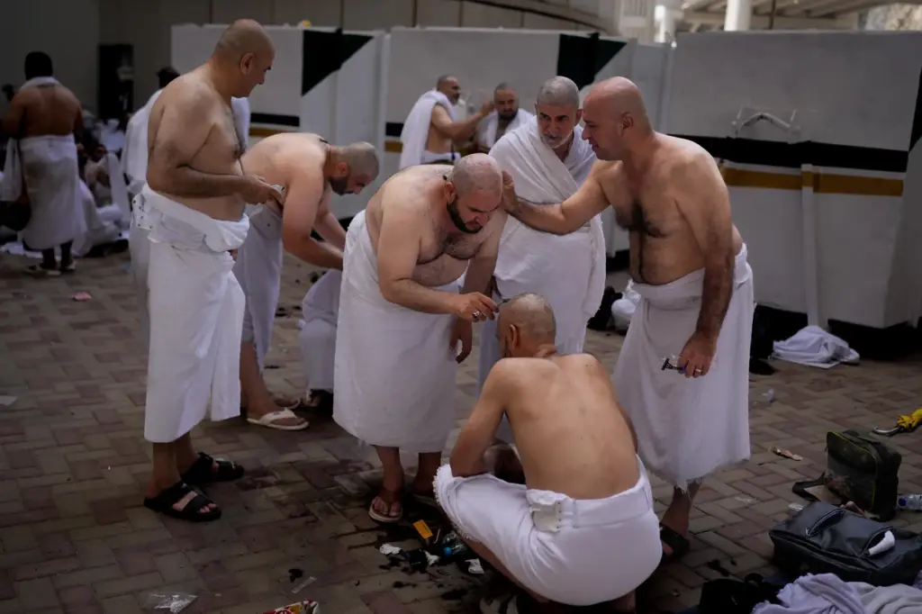 Muslim pilgrims shave each other’s heads, during a ritual known...