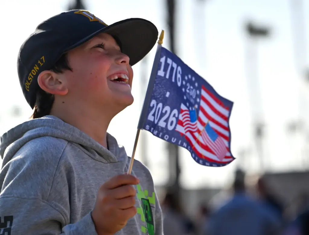 Colston Valenzuela, 8, waves an American semiquincentennial flag during a...