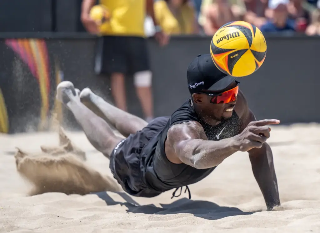 Ahmed Tijan dives in the sand to dig the ball,...