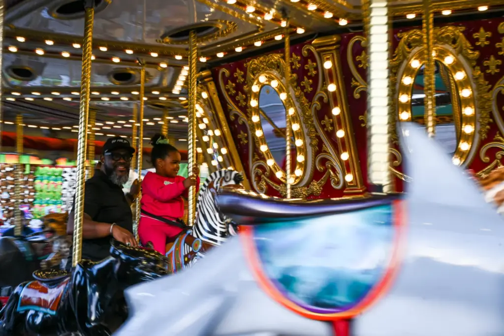 Darold Ross and daughter Amina Ross enjoy the carousel during...