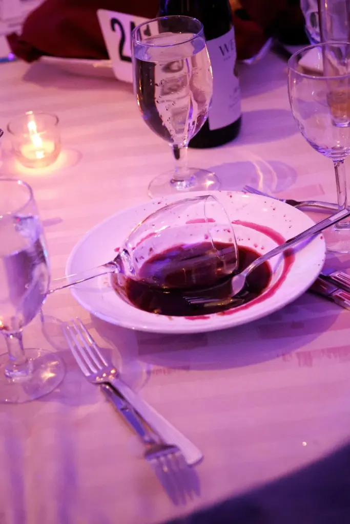A tipped-over wine glass sits in a bowl on an abandoned table.