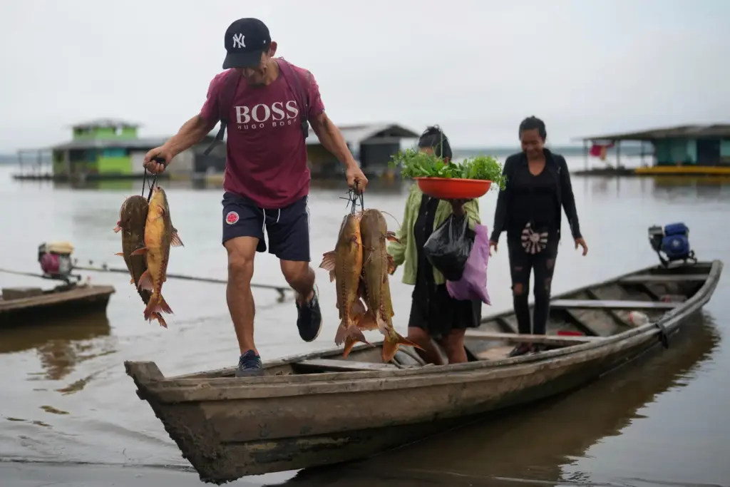 FILE – A man unloads fresh fish from a boat...
