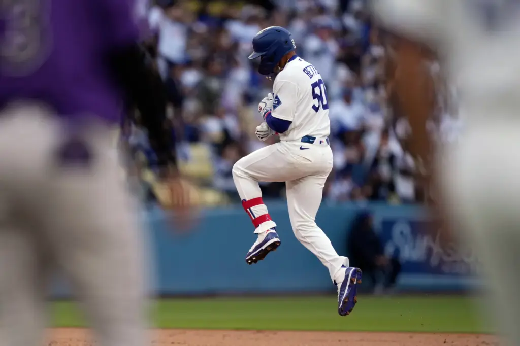 The Dodgers’ Mookie Betts jumps as he runs the bases...