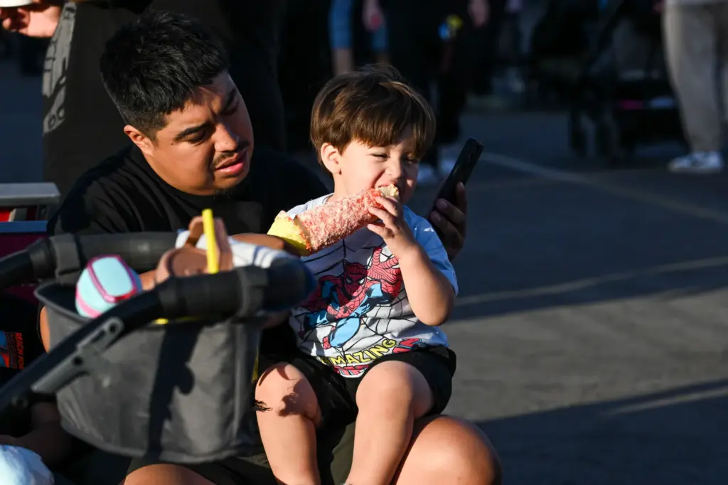 Anthony Hernandez feeds his son Johnny elote corn during the...