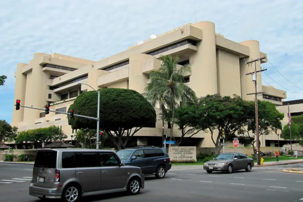 Cars pass in front of the federal building housing the U.S. District Court in Honolulu.