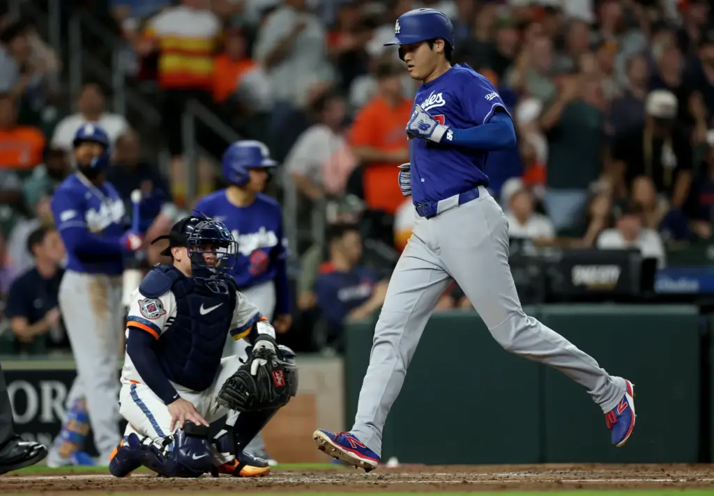 Dodgers star Shohei Ohtani crosses home plate to score a...
