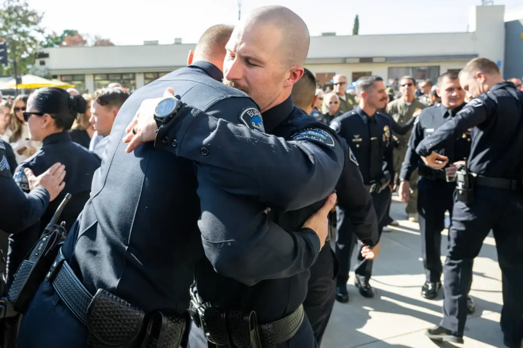 Spike’s handler, Burbank Police Officer Salas hugs a colleague during...