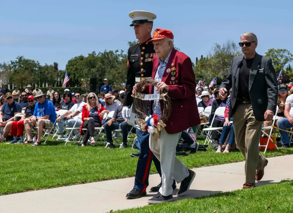 Marine Corps veteran Charles Cram, 100, center, is helped by...