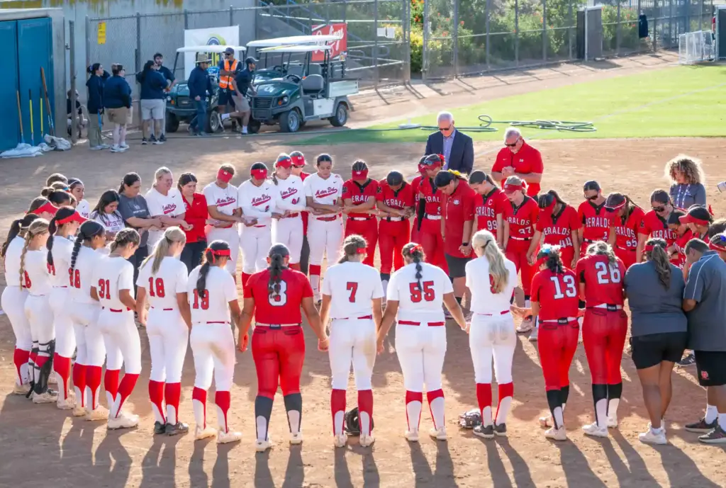 Whittier Christian and Mater Dei players pray together following the...