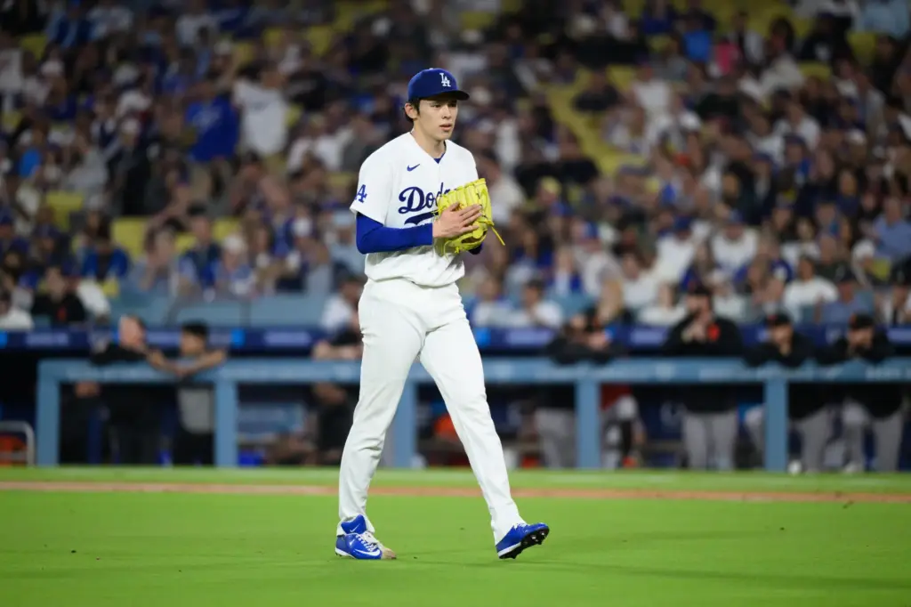 Dodgers starting pitcher Roki Sasaki claps as he walks to...