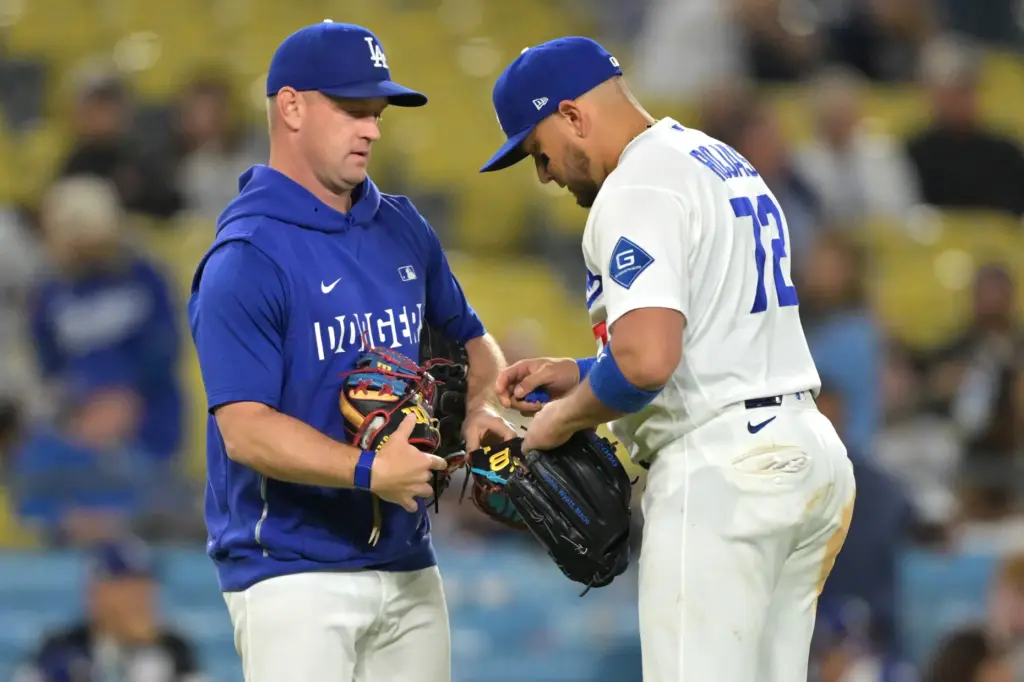Dodgers infielder Miguel Rojas, right, chooses his glove before pitching...