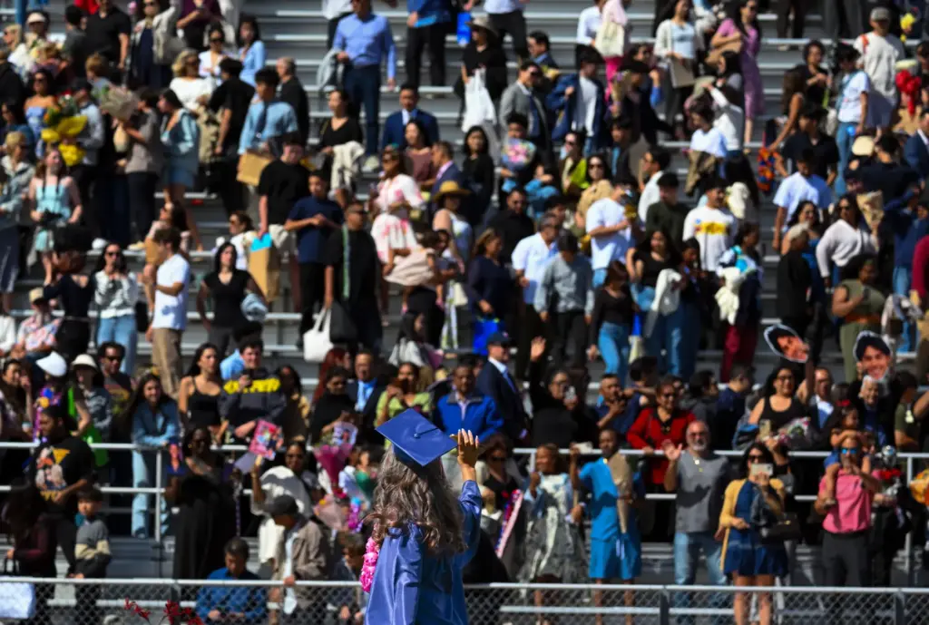 A graduate waves tot he crowd at the end of...