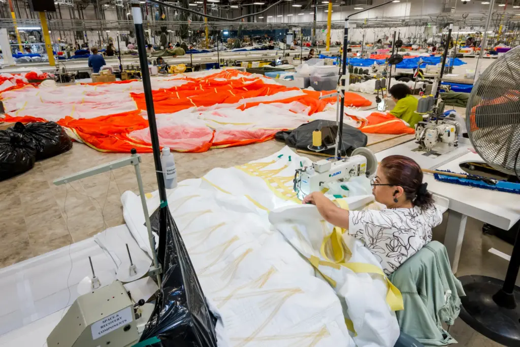 A sewing machine operator works on one of three parachutes...