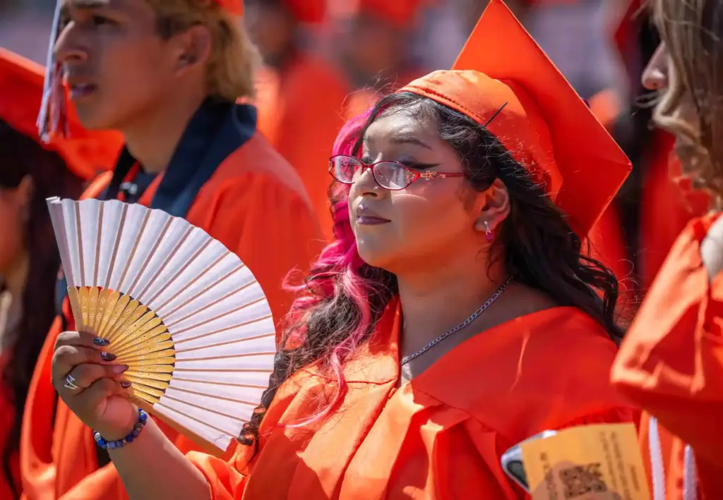 One Orange High School graduate uses a fan to keep...