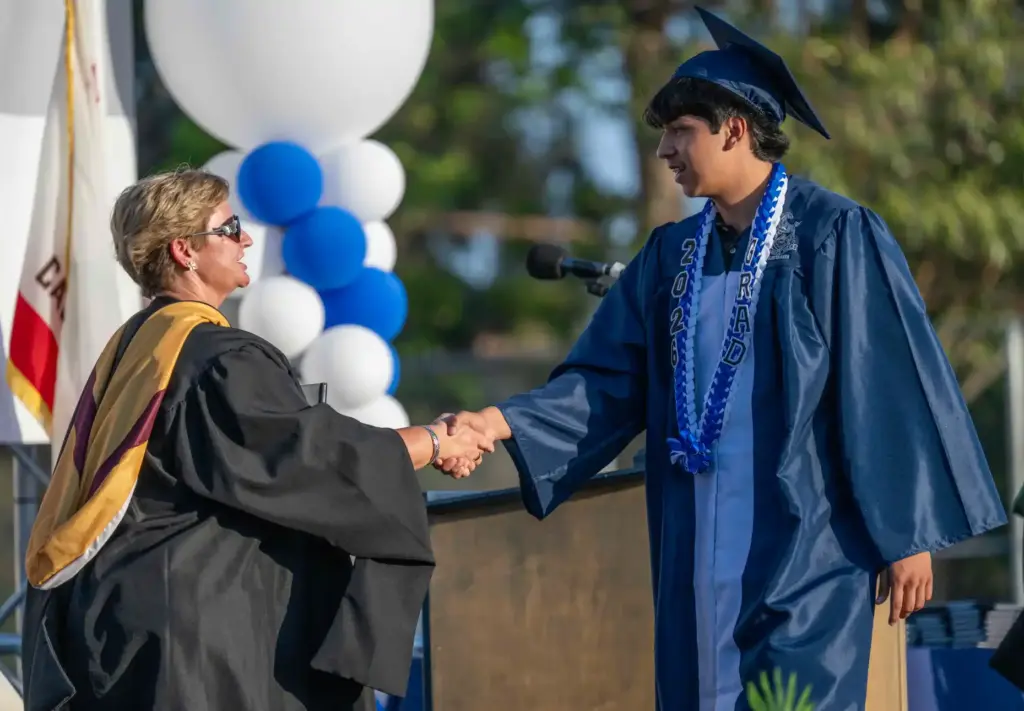 Diego Almada shakes hands with Principal Alicia Foulk while walking...
