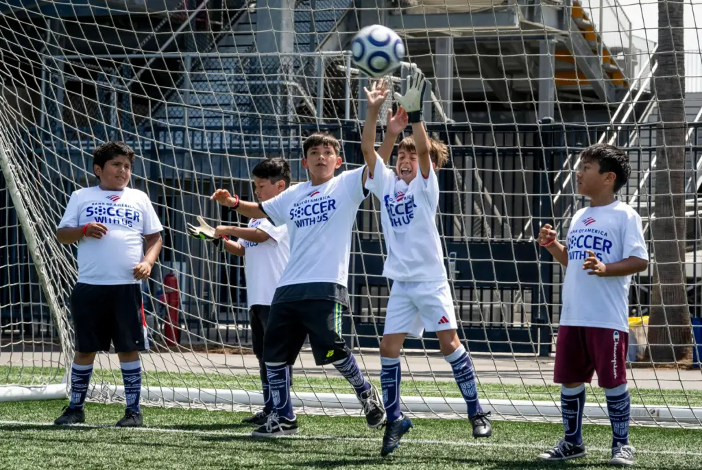 Kids team up to protect the goal during a soccer...