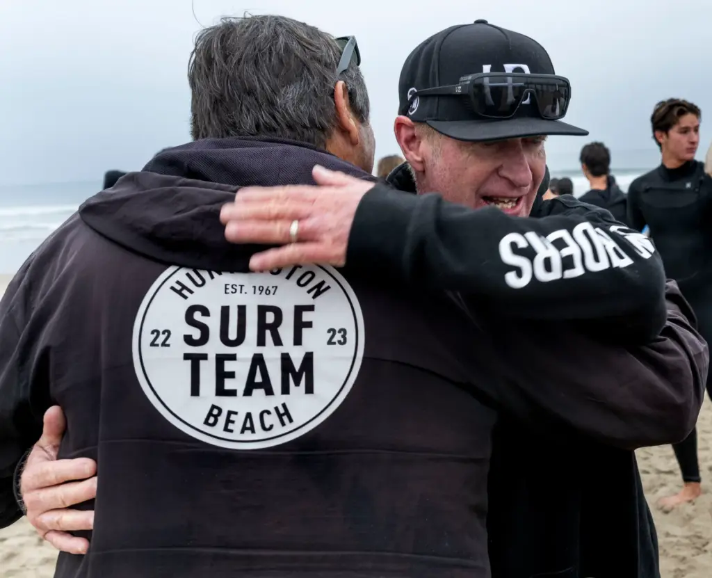 Huntington Beach High School alumnus George Lambert, facing, hugs surfing...