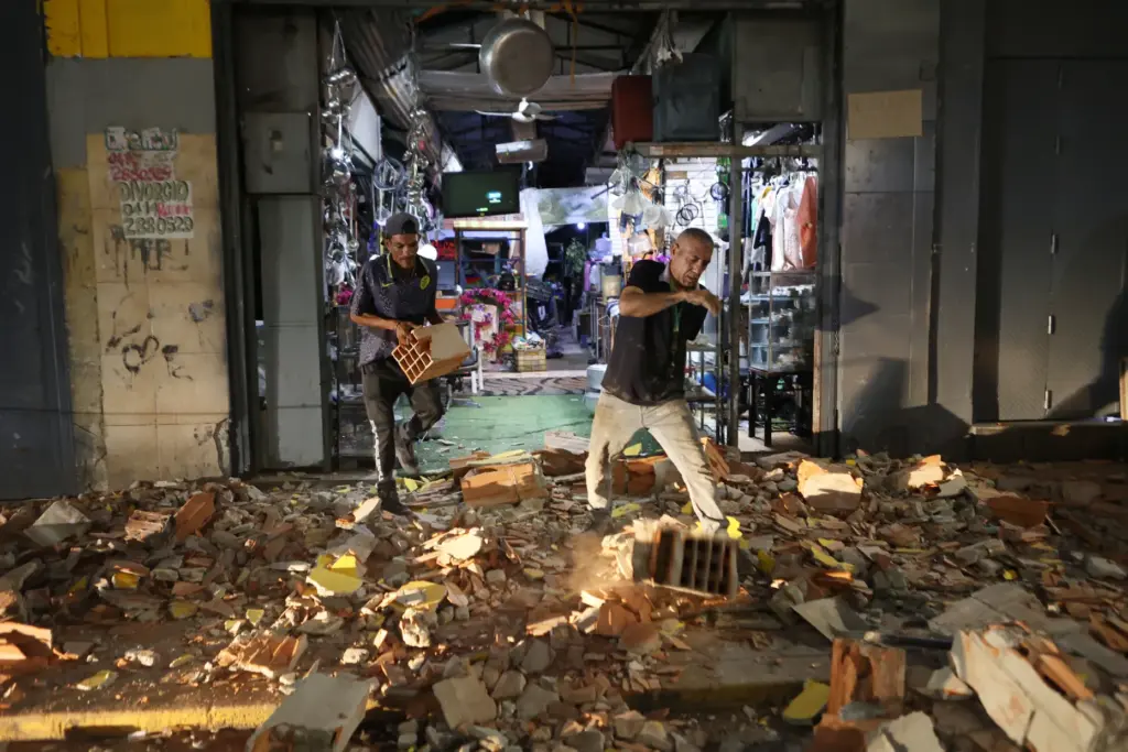 Men walk among rubble after an earthquake in Caracas, Venezuela,...