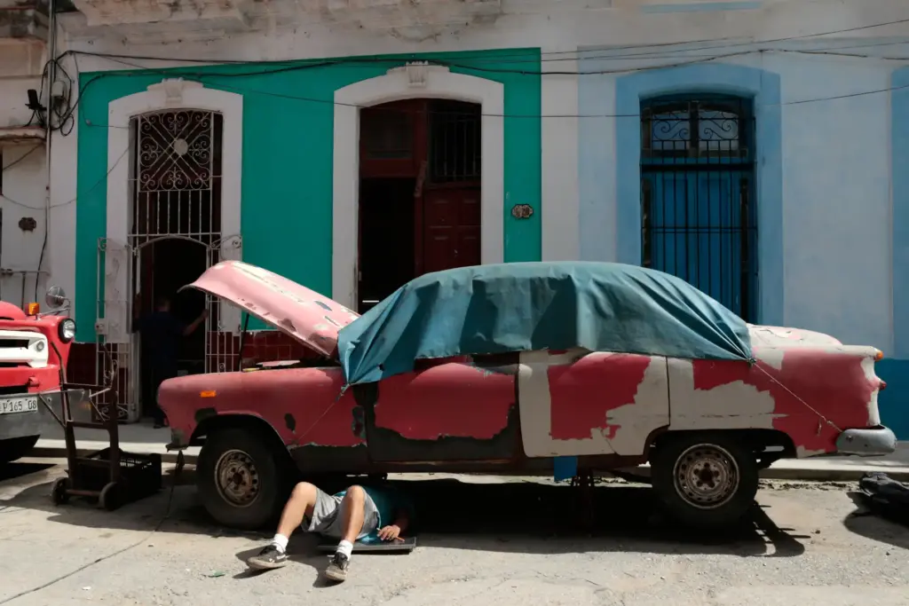 A man works on a classic American car in Havana,...