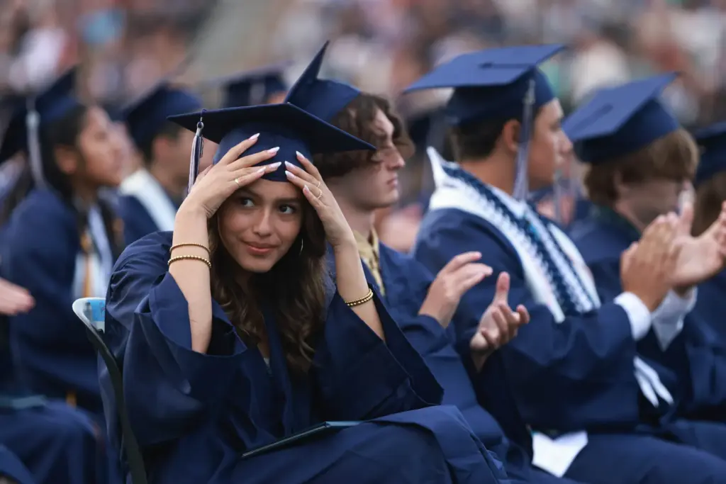 A Graduate adjust her mortar board from the wind during...