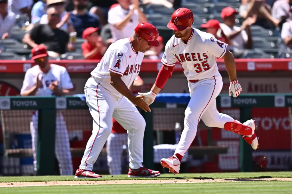 Angels’ Donovan Walton (35) is greeted by third base coach...